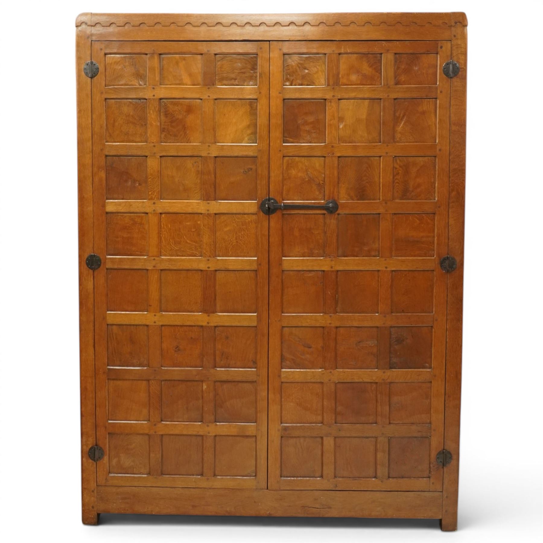 Mouseman - early-to-mid-20th century figured panelled and adzed double wardrobe of large proportions, the arcade carved cresting rail over two doors with adzed and figured oak panels, with wrought metal hinges and latch, relief carved mouse signature, the interior fitted with hanging rail, by the workshop of Robert Thompson, Kilburn