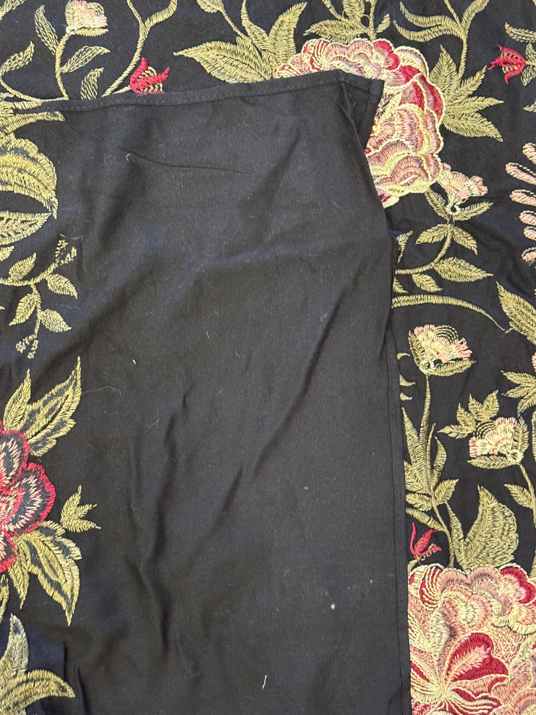 Embroidered Karandi fabric runner, the field featuring a black ground with an all-over floral design, including large pink and cream roses, accompanied by green leaves and small blossoms, bordered by plain sections at each end