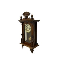 An early 20th century German wall clock with an 8-day HAC spring driven movement striking the hours on a coiled gong, in a mahogany case with a shaped pediment and turned columns flanking a full-length glazed door, with a two-part dial enamel with Roman numerals, minute track and pierced gothic designed hands, gridiron pendulum and beat plate. With Key.





