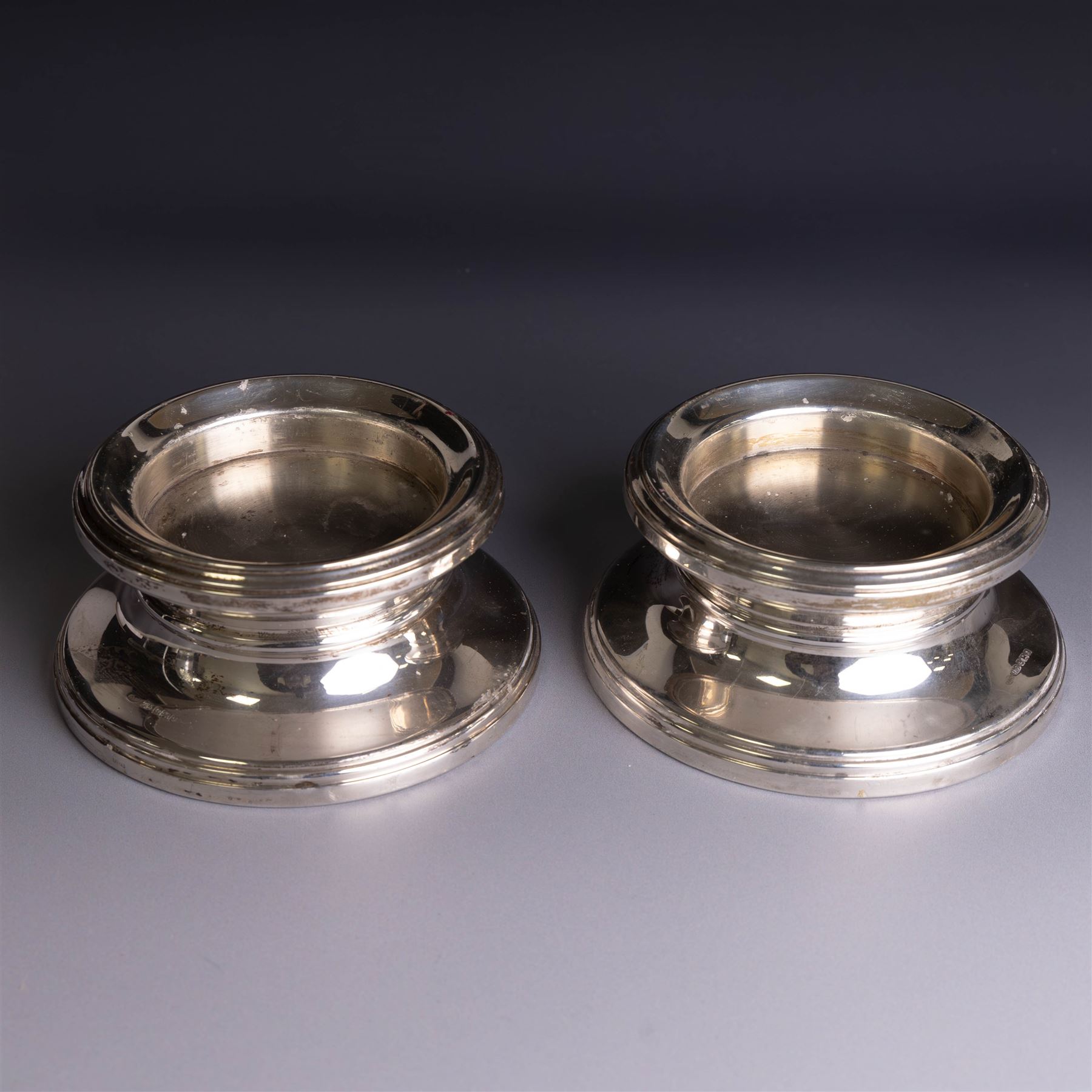 Pair of modern silver mounted candle holders, of circular stepped form, hallmarked Broadway & Co, Birmingham 2006, H5.5cm, D11cm