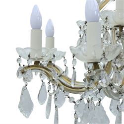 20th century Maria Theresa style twelve branch chandelier, gilt metal frame with scrolling arms clad in moulded glass, the central baluster stem issuing twelve candle sconces with glass drip pans, hung with faceted pendants and swags of cut glass beads 