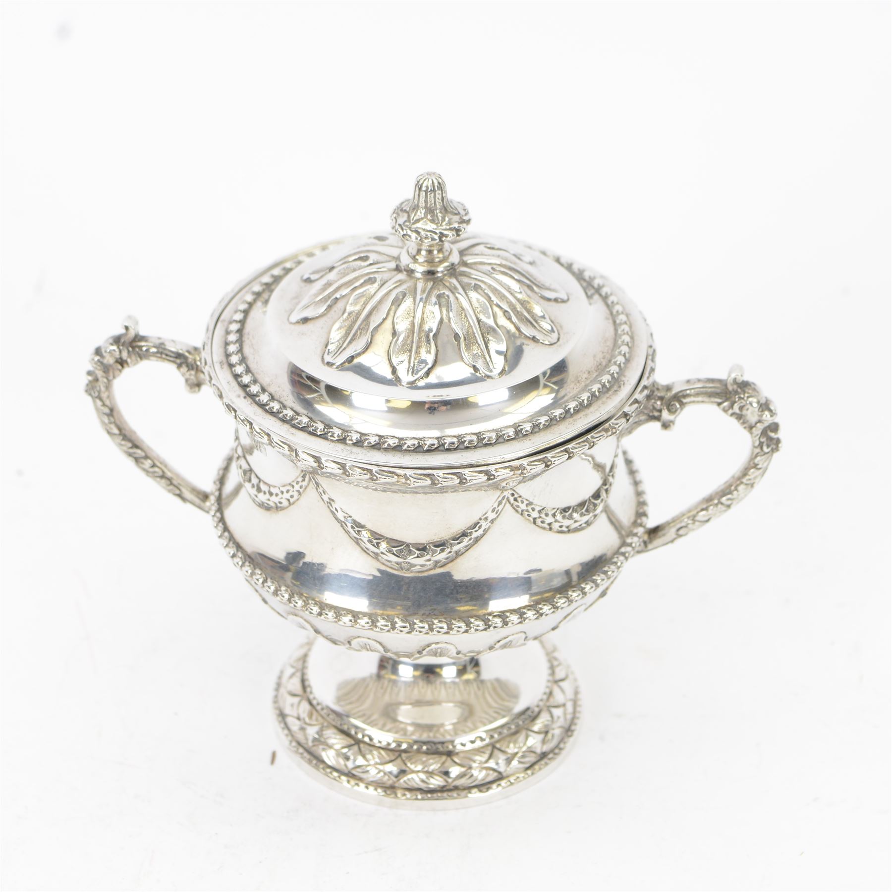 Early 20th century silver twin handled pedestal bowl and cover, the wasted body with embossed husk swag and band, above stiff leaf detailed lower section, and twin zoomorphic mask detailed handles, the slightly domed cover with conforming embossed decoration, upon a spreading circular foot, hallmarked George Nathan & Ridley Hayes, Chester 1908, H15cm
