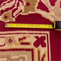 Large Persian Savonnerie-inspired style flatweave kilim, crimson field with central stylized palmette medallion with bold scrolling vinery and angular floral motifs between multiple guard stripes, rendered in tones of soft cream, pale sage, and muted terracotta, with fringe ends 