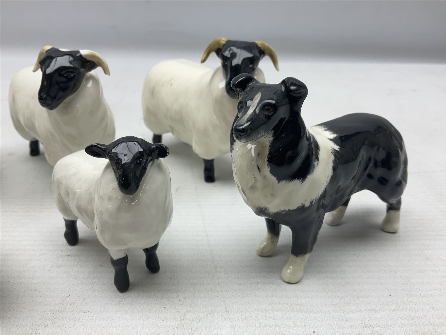Seven Beswick figures of sheep comprising three ewes and four lambs, together with a figure of a sheepdog (8)
