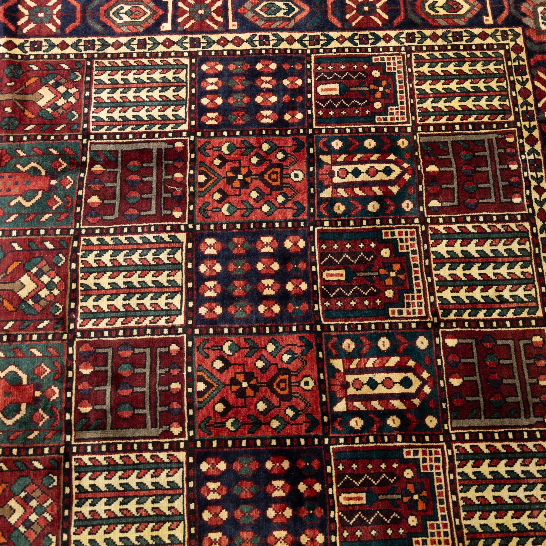 Bakhtiari wool rug, compartmented garden design field with panels of stylised trees, flowers and geometric motifs, enclosed by dark blue main border with repeating floral medallions and guard stripes