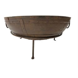 Circular riveted iron fire pit, strapwork sides with twin handles on stand, with grate