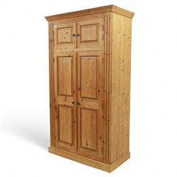 Modern stripped pine double wardrobe, with stepped cornice over upper cupboard doors and two full-height fielded panel doors, fluted stile detailing, ebonised knob handles, and plinth base