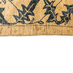 Late 20th century Turkish hand-woven carpet, golden beige field decorated with a repeating lattice of stylized medallions enclosing boteh and angular foliate motifs linked by issuing scrolling vinery within a border of complementary stylized leaf scrolls