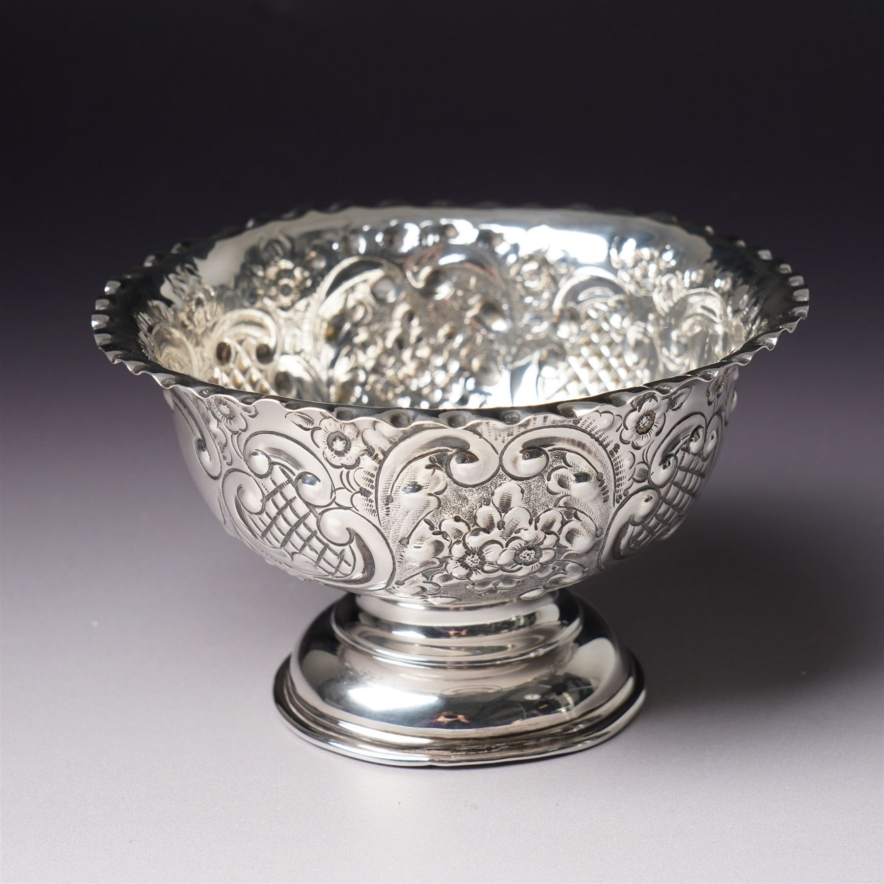 Edwardian silver bowl with embossed decoration on a short pedestal foot D11cm Birmingham 1904 Maker A & J Zimmerman Ltd and a modern silver coaster with turned wooden base D9.5cm Sheffield 2001 (2)