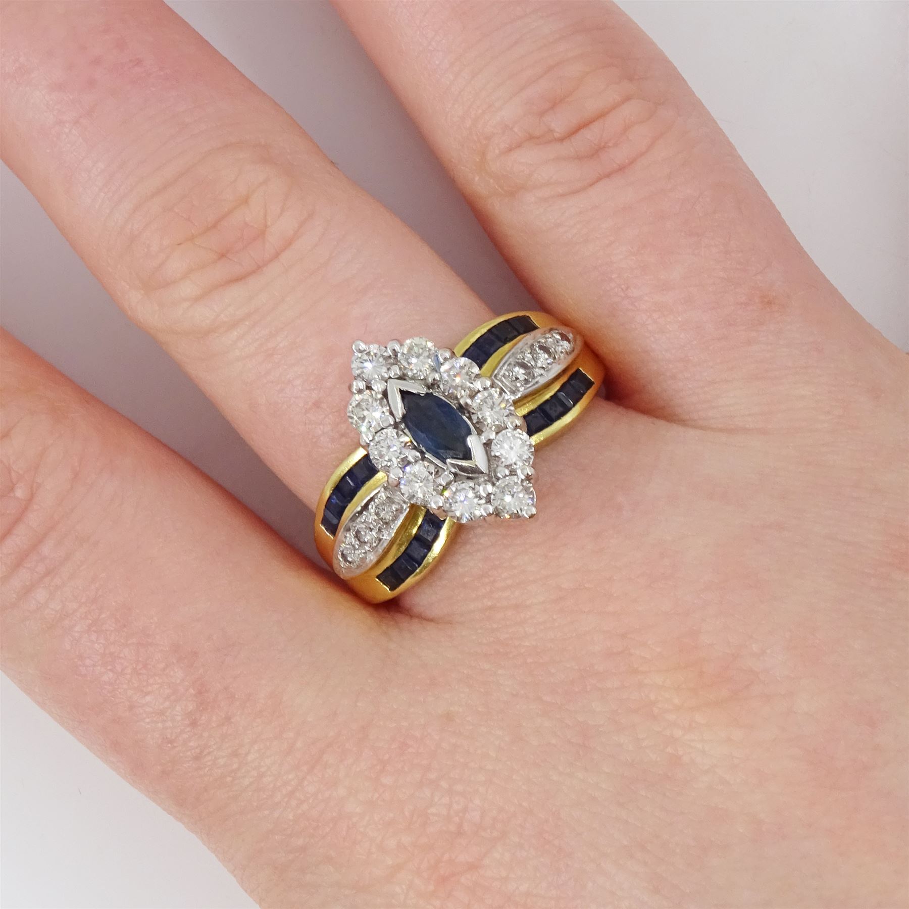 18ct gold sapphire and diamond cluster marquise shaped ring, single marquise cut sapphire, surrounded by ten round brilliant cut diamonds, each shoulder set with three round brilliant cut diamonds and ten calibre cut sapphires, hallmarked, total diamond weight approx 0.90 carat