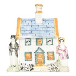 19th Century Staffordshire pearlware Prattware type money box, modelled as a houe with two figures to the front corners, H13cm