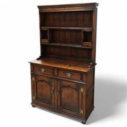 Contemporary georgian style oak dresser, open rack top with two shaped shelves and small side drawers, base with rectangular top over two drawers with brass swing handles, twin arched panelled doors below, on bracket feet