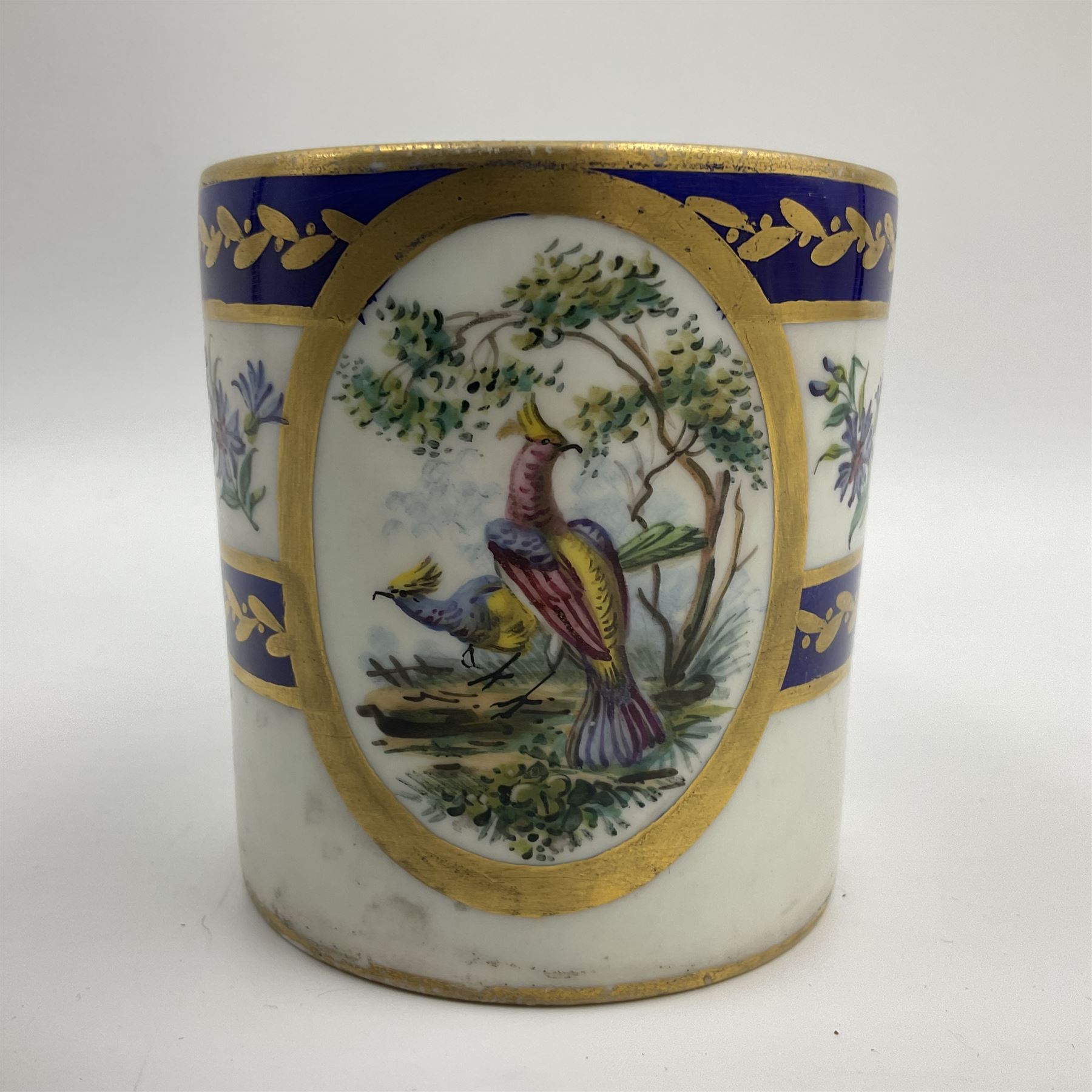 19th Sèvres style porcelain cup and saucer, the cup painted with a figural scene, against a scalloped border of scrolling floral swags on a blue ground, together with a Sèvres soft paste porcelain coffee can and saucer, painted with panels of exotic birds, roses and a border of cornflowers, LL monogram enclosing date letters H above painters mark, coffee can H6.5cm, saucer D13.5cm (2)