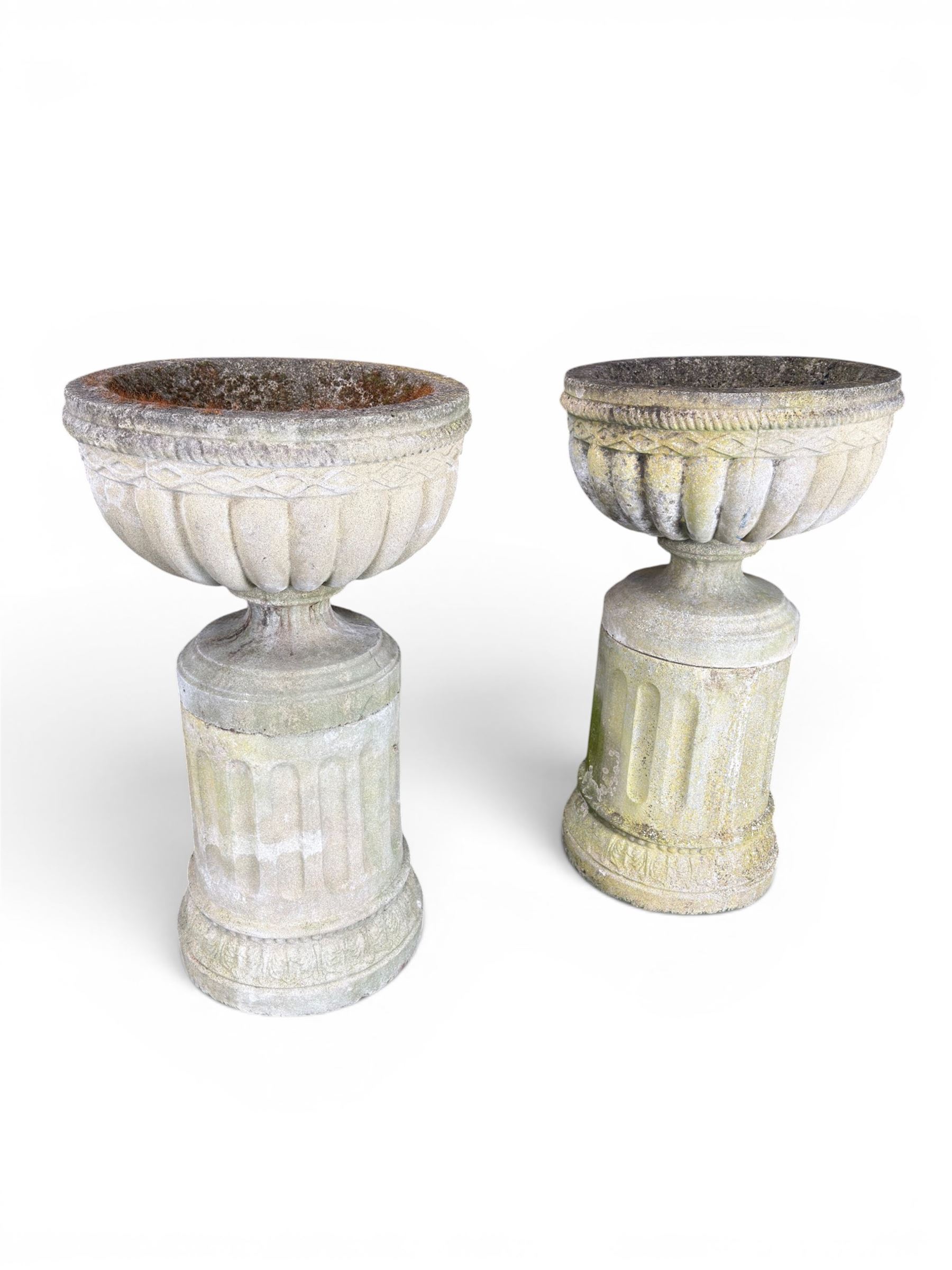 Four 20th century good quality weathered cast stone pedestal urns, circular lobed bowls with rope twist and lattice border, raised on squat base with fluted columns