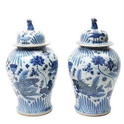 Pair of Chinese blue and white jars and covers, of baluster form, hand painted with fish a...