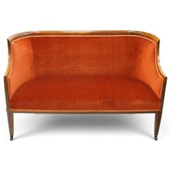 Edwardian inlaid mahogany tub two seater settee, traditional shape with satinwood stringing, upholstered in crimson fabric with sprung seat, on square tapering supports with castors