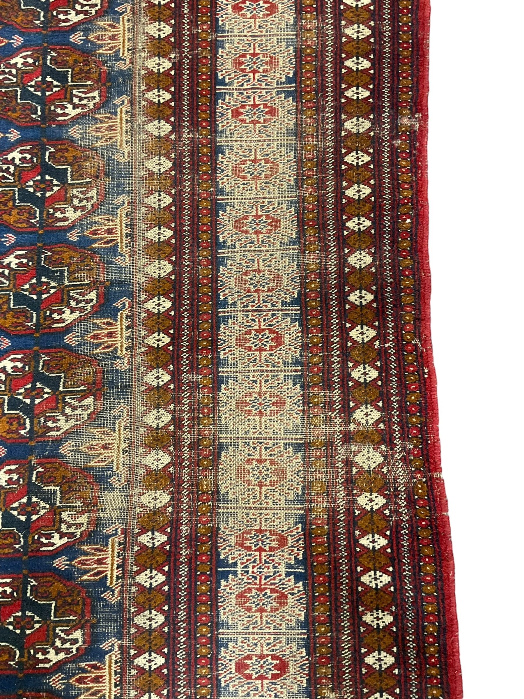 Persian indigo Bokhara rug, decorated with three rows of Gul motifs