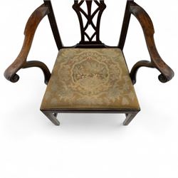 19th-century Chippendale Revival design mahogany oversized high-back armchair, serpentine crest carved top rail above pierced back splat with interlaced ribbon carving and geometric fretwork design, and outward scrolling arms above drop-in needlework seat on square chamfered legs 