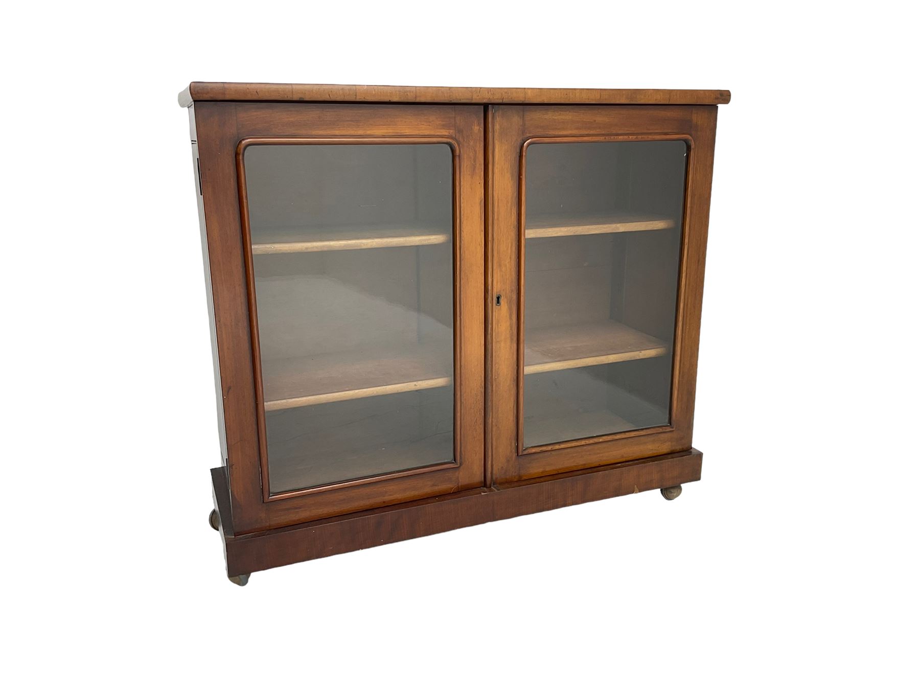 Victorian bookcase, rectangular top over two glazed doors enclosing two shelves, on skirted base
