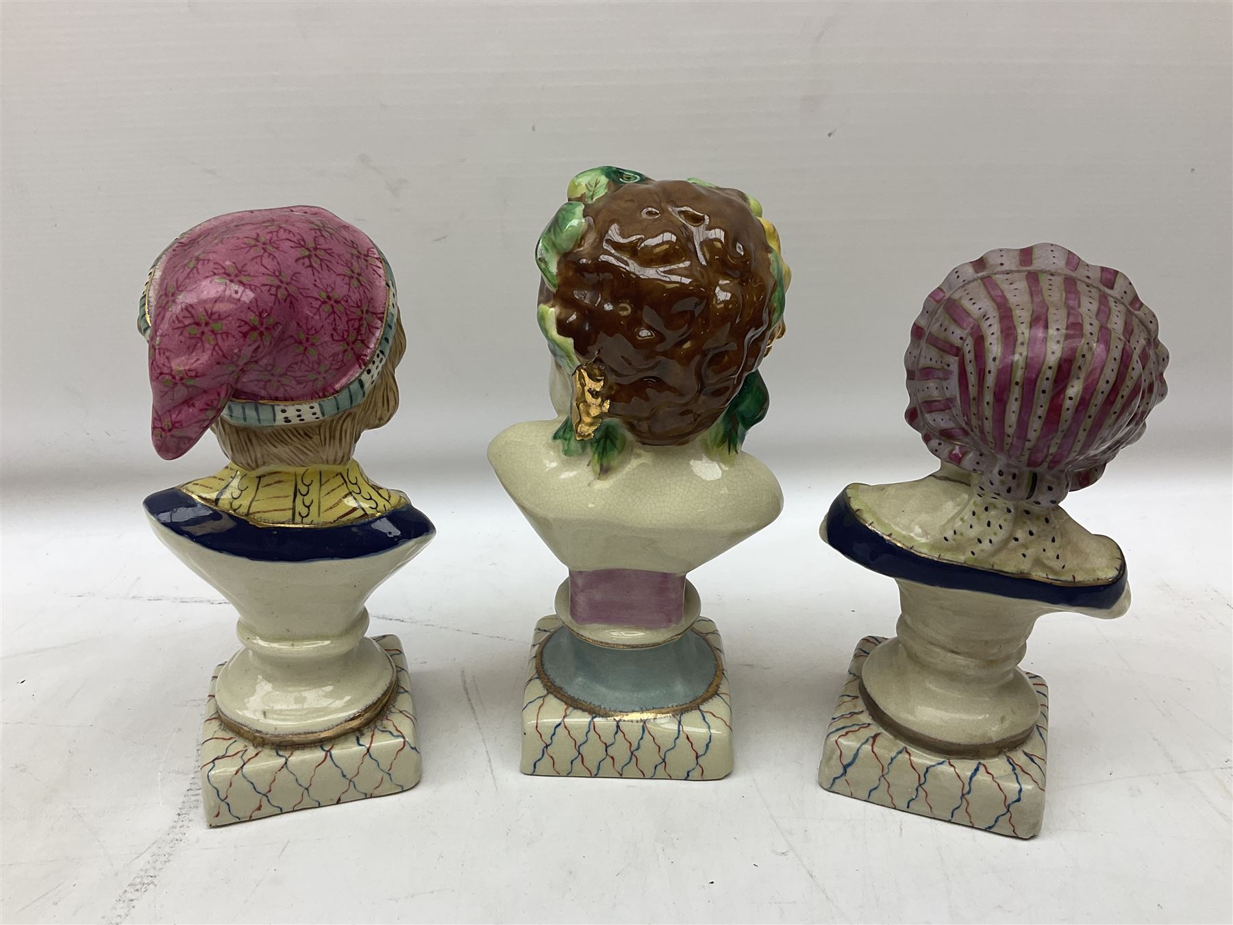 19th century pair of hand painted ceramic busts of children, together with a third similar example of a putti with a crown of ivy, tallest H23cm 