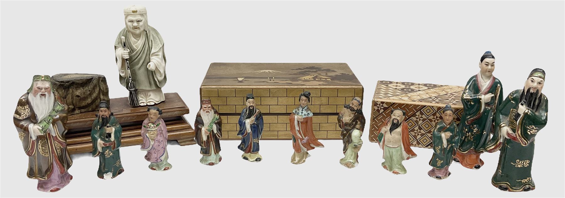 Japanese parquetry puzzle box L12cm; another Japanese puzzle box with marquetry top of Mount Fuji; eleven graduated Chinese figures including immortals; and Chinese figure of a lady standing on a hardwood base next to a horn table (14)