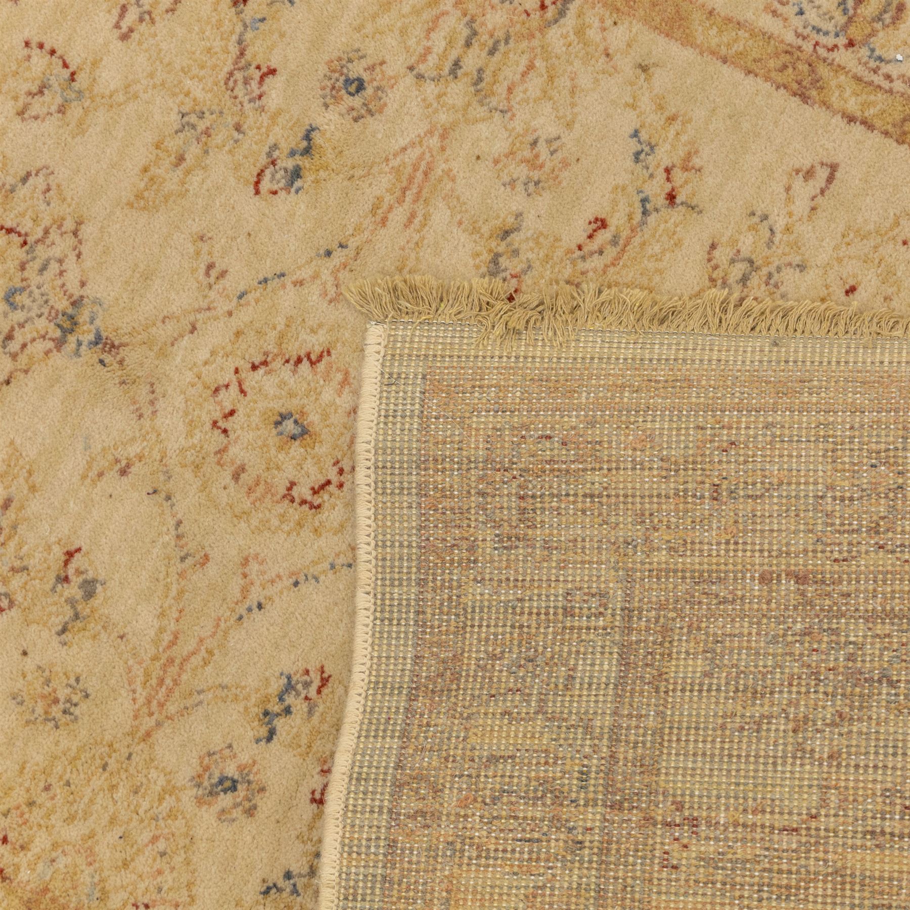 Cream ground wool rug, with faded floral medallion and scrolling foliate design, enclosed by matching floral border in beige, soft red and blue tones