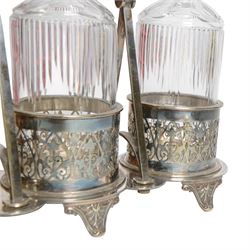 Late 19th century silver plated Silber & Fleming triple decanter stand, the three cut glass decanters with spire stoppers housed within foliate and scroll pierced bottle sleeves, upon a tripart base with six scroll feet, the base mounted with articulated x-frame curved handle, including handle when positioned upright H35.5cm, W34cm