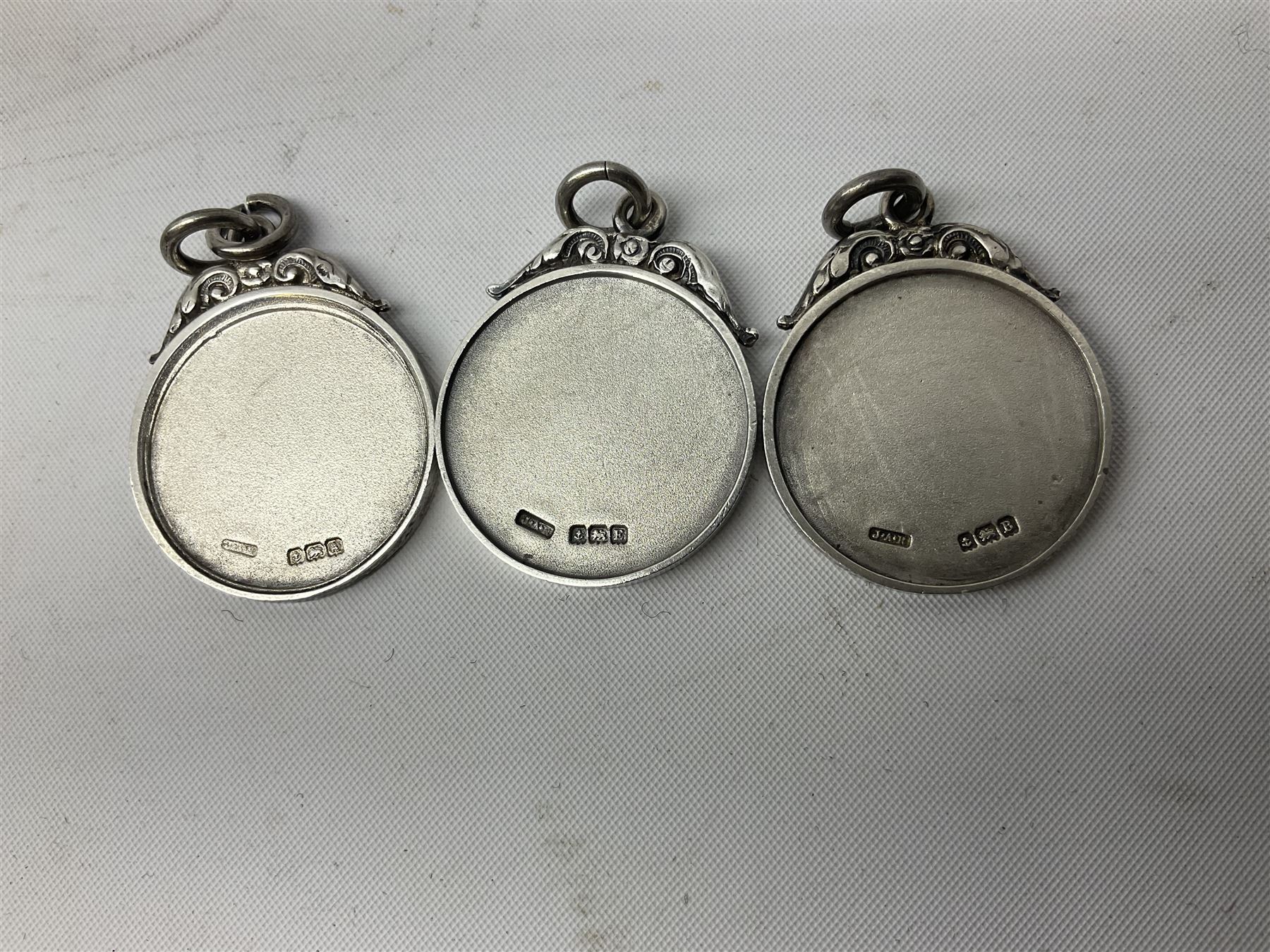 Set of three Yorkshire Miniature Rifle Association hallmarked silver and enamel fob medals, Birmingham 1925, 1926 & 1929; together with six silver plated coffee spoons each engraved with crossed rifles to the terminal (9)