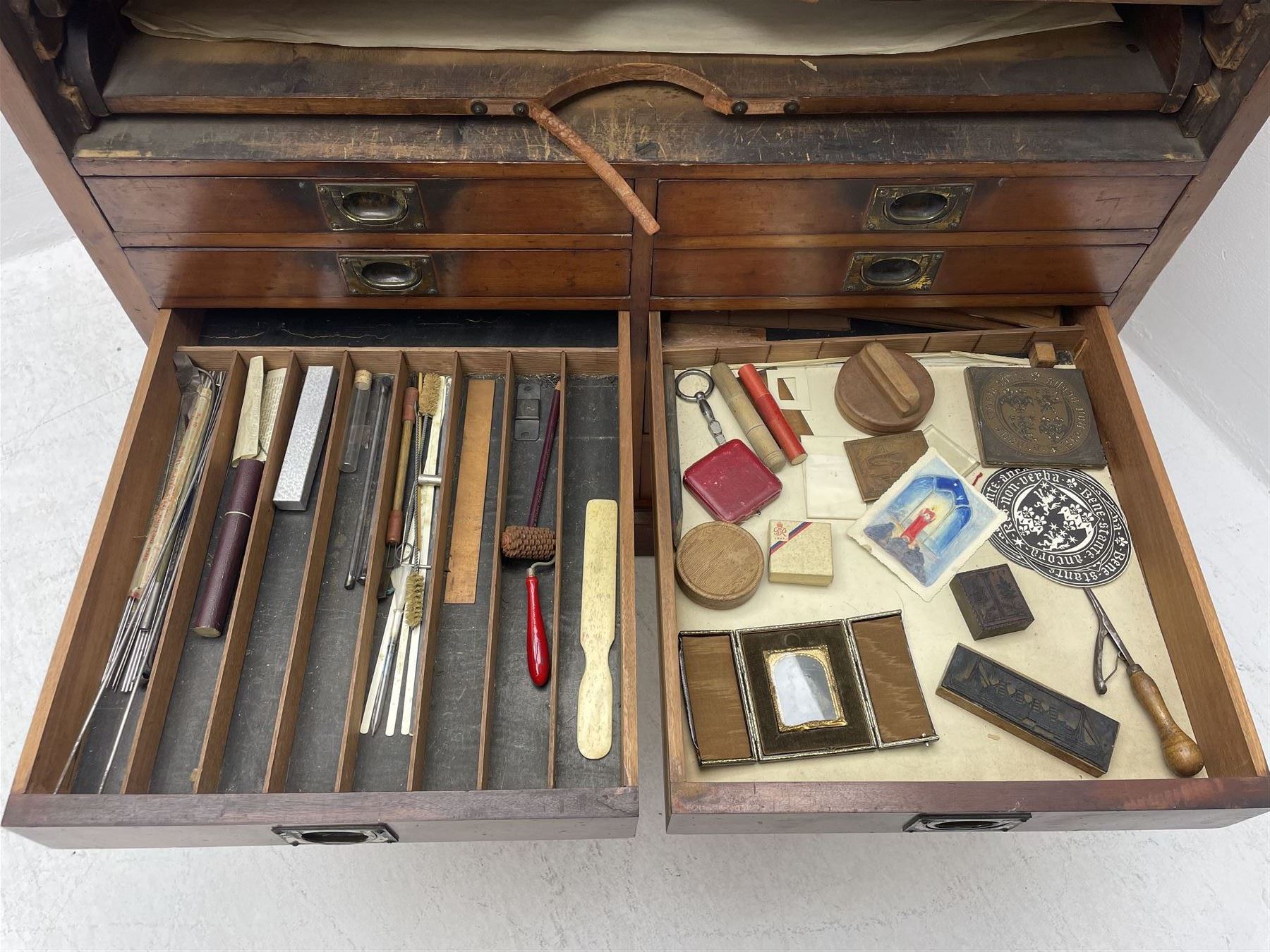 Edwardian mahogany artist's cabinet once belonging to the British artist Eli Marsden Wilson (1877-1965), raised panelled back mounted by carved brackets, sloped and hinged glazed lid enclosing paint holders and compartments, up-and-over panelled door revealing three slides, fitted with two banks of five graduating drawers with recessed brass handles, on skirted base.

Together with a quantity of artists' equipment and tools including paints, paintbrushes, charcoal, chalks, etc. and various prints relating to the life of the artist, including Quaker anti-war posters, Victorian Stevengraphs, and various chromolithographs 

Provenance: Removed from the studio of Eli Marsden Wilson. The cabinet comes to us for sale through family descent. The vendor is descendant of Marsden. Many further etchings removed from the cabinet are being sold in the Spring Art Sale, Friday 15th March 2024, Lots 265-271.

Notes: born in Ossett, Eli Marsden Wilson was the only son of Alfred Wilson, a foreman beamer, and Emma Marsden, and had five sisters. After studying at Wakefield College of Art, he moved to the Royal College of Art in London, where he became a pupil of Sir Frank Short. He had his first exhibit at the Royal Academy in 1905, the same year he married fellow artist Hilda Mary Pemberton.

A Quaker, vegetarian, and pacifist, he was a conscientious objector in World War I and as such was imprisoned in 1917 for two years. In September 1922 he was commissioned by Princess Marie Louise to produce miniature etchings for Queen Mary's Dolls' House at Windsor Castle; two such etchings are being sold in the Spring Art Sale, Friday 15th March 2024, Lot 265.