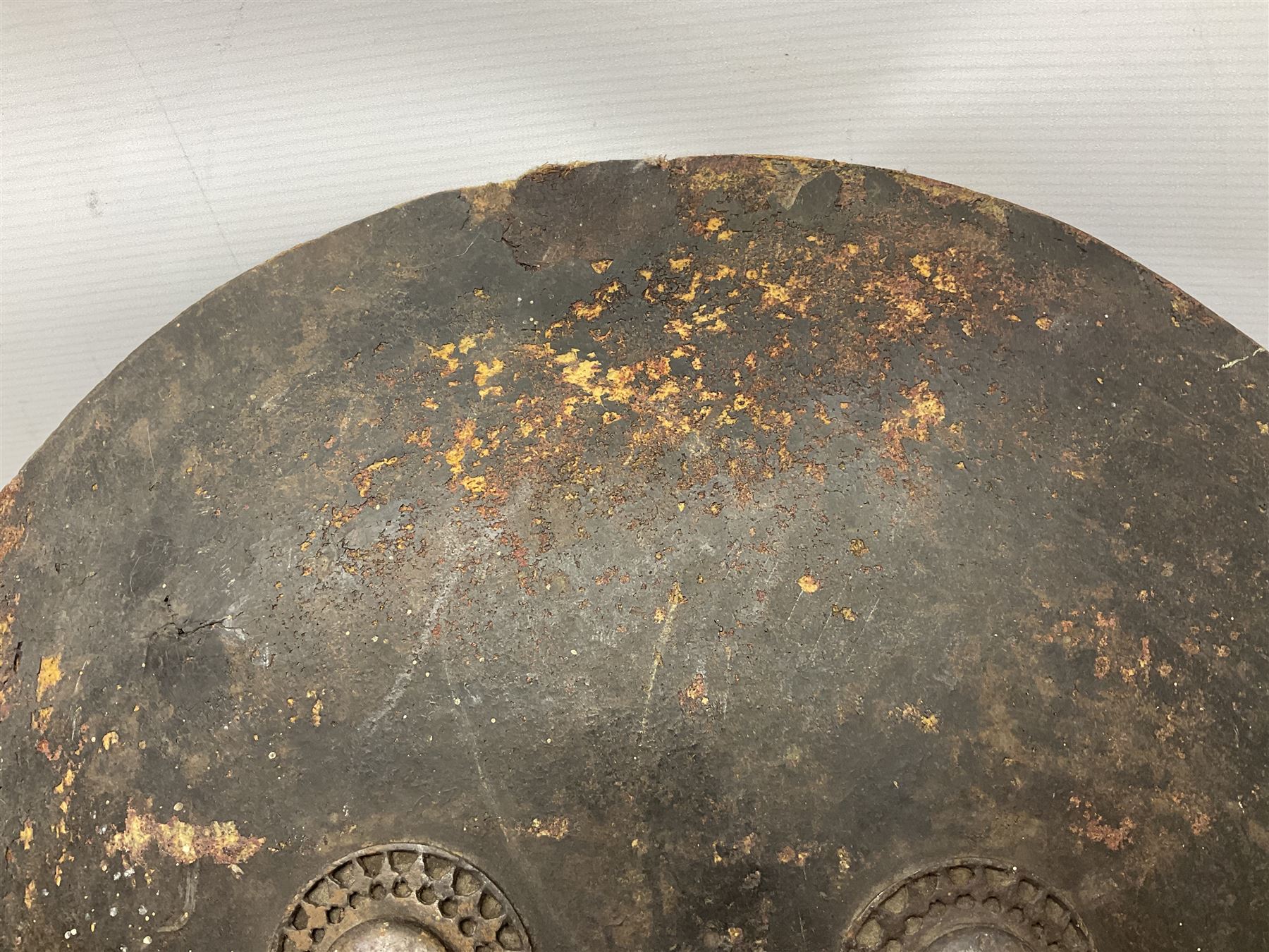 Indian black lacquered hide shield/dhal, of circular convex form fitted at its centre with four pierced iron bosses, each of hemispherical form with wide brims, the bosses corresponding on the inside with four iron rings for enarmes D53.5cm