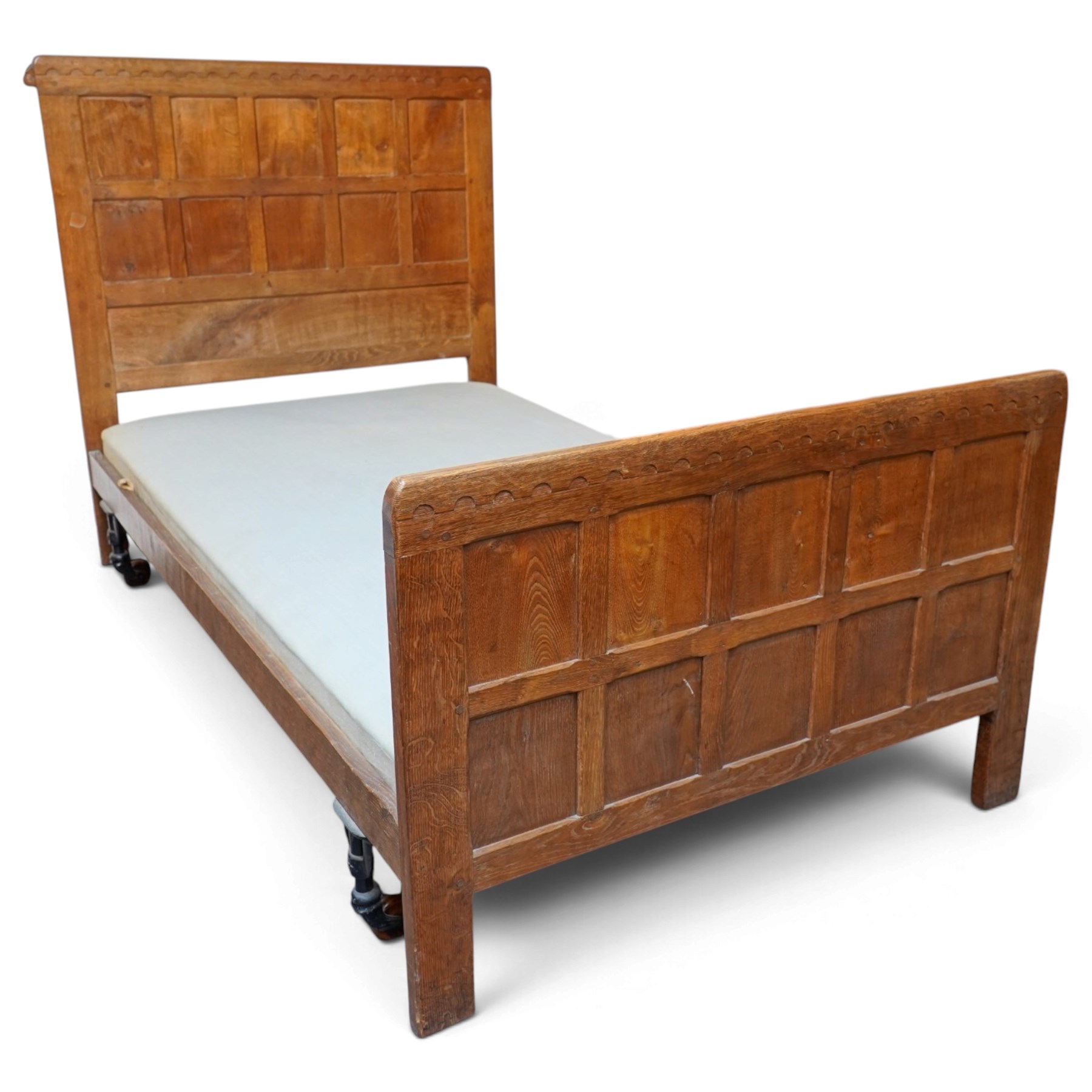 Mouseman - pair of 1930's adzed and panelled oak single beds, the head and foot-boards with arcade-carved cresting rails above adzed panels, with Vibase mattress supports, carved with mouse signature, by the workshop of Robert Thompson of Kilburn