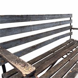 19th century wrought iron strapwork and slatted wood garden bench, the arm terminals and end supports of scrolling form