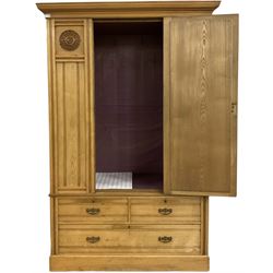 Edwardian light oak double wardrobe, single mirrored door flanked by rosette carved panels, above two short and one long drawer, on skirted base, with all over reeded and moulded decoration