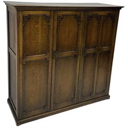 Early 20th century oak triple wardrobe, three panelled doors with geometric mouldings and fretwork spandrels, the interior fitted with slides and hanging rail
