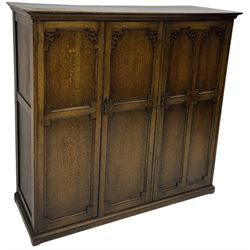 Early 20th century oak triple wardrobe, three panelled doors with geometric mouldings and fretwork spandrels, the interior fitted with slides and hanging rail