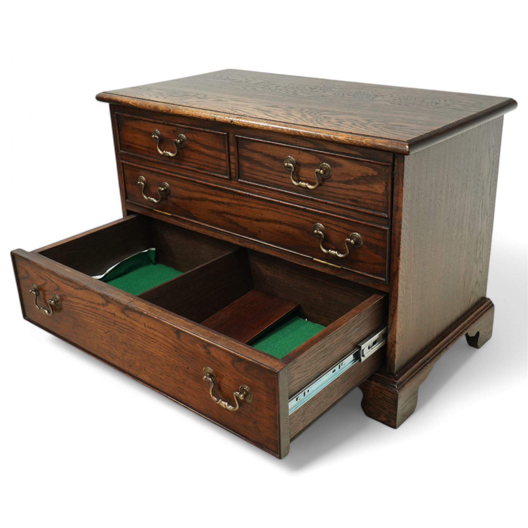 T & G style solid oak television cabinet, rectangular moulded top over two short and two long drawers with brass swing handles, the upper frieze drawer front hinged and fitted with stay to reveal pull-out shelf, open compartment above with circular cable aperture to rear, on bracket feet