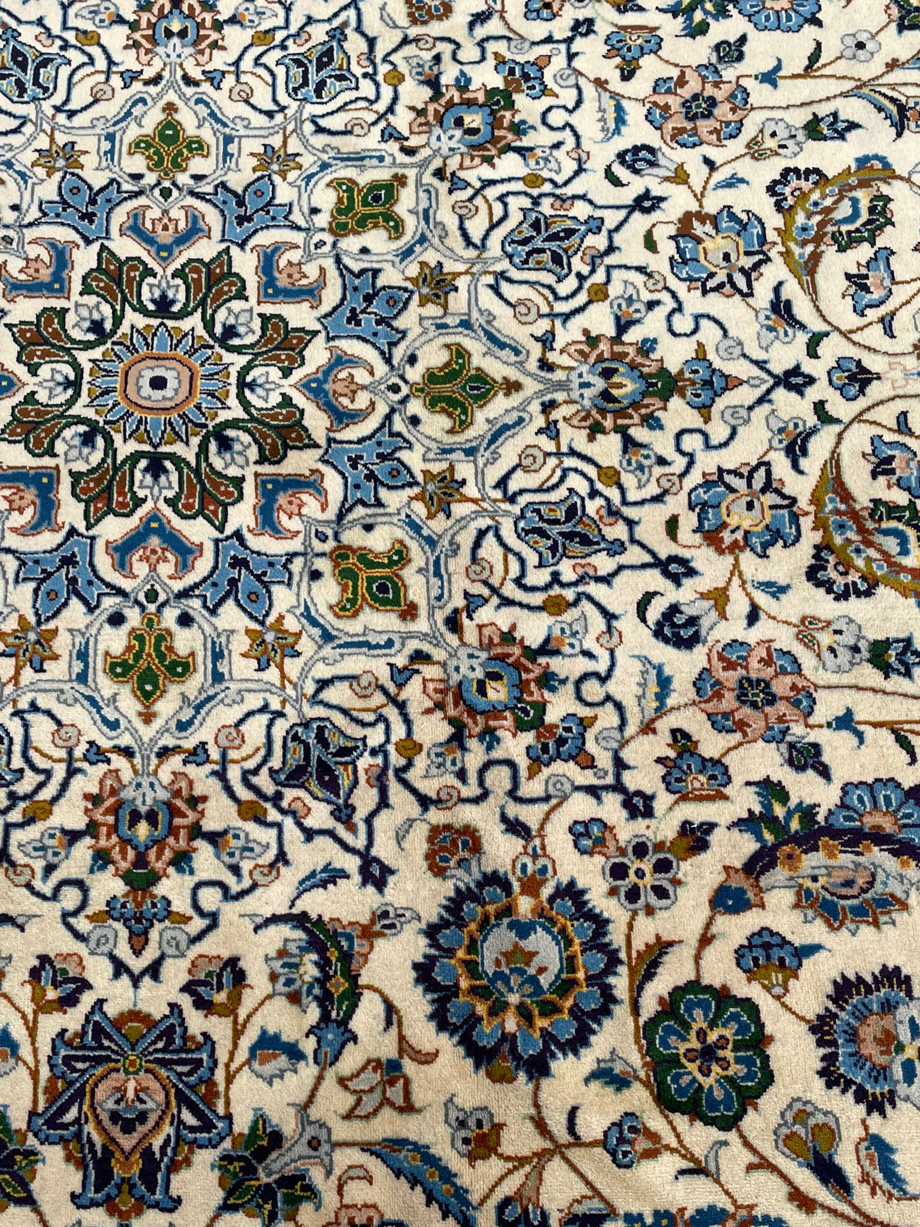 Persian Kashan ivory ground carpet, the interlaced foliate medallion surrounded by trailing plant motifs interlaced with scrolls, the guarded border with repeating stylised flower heads