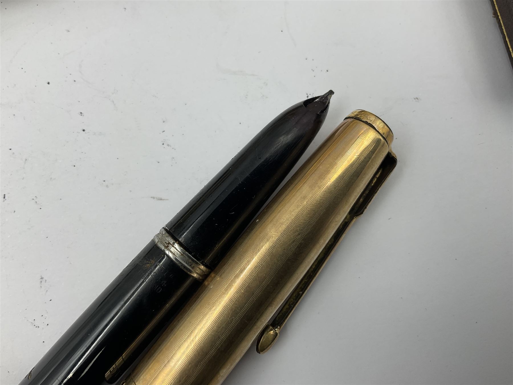 Three parker fountain pens, one example with 14ct gold plated cap and personal engraving, in Parker 51 box, together with a silver Sampson Mordan Everpoint propelling pencil with personal engraving and a silver cased fountain pen with 14ct gold nib and a souvenir bronze Dollfus-Mieg medallion, awarded to John G Sedorski, in fitted case 