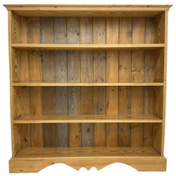 20th century pitch pine open bookcase, fitted with three shelves, on bracket feet with shaped apron