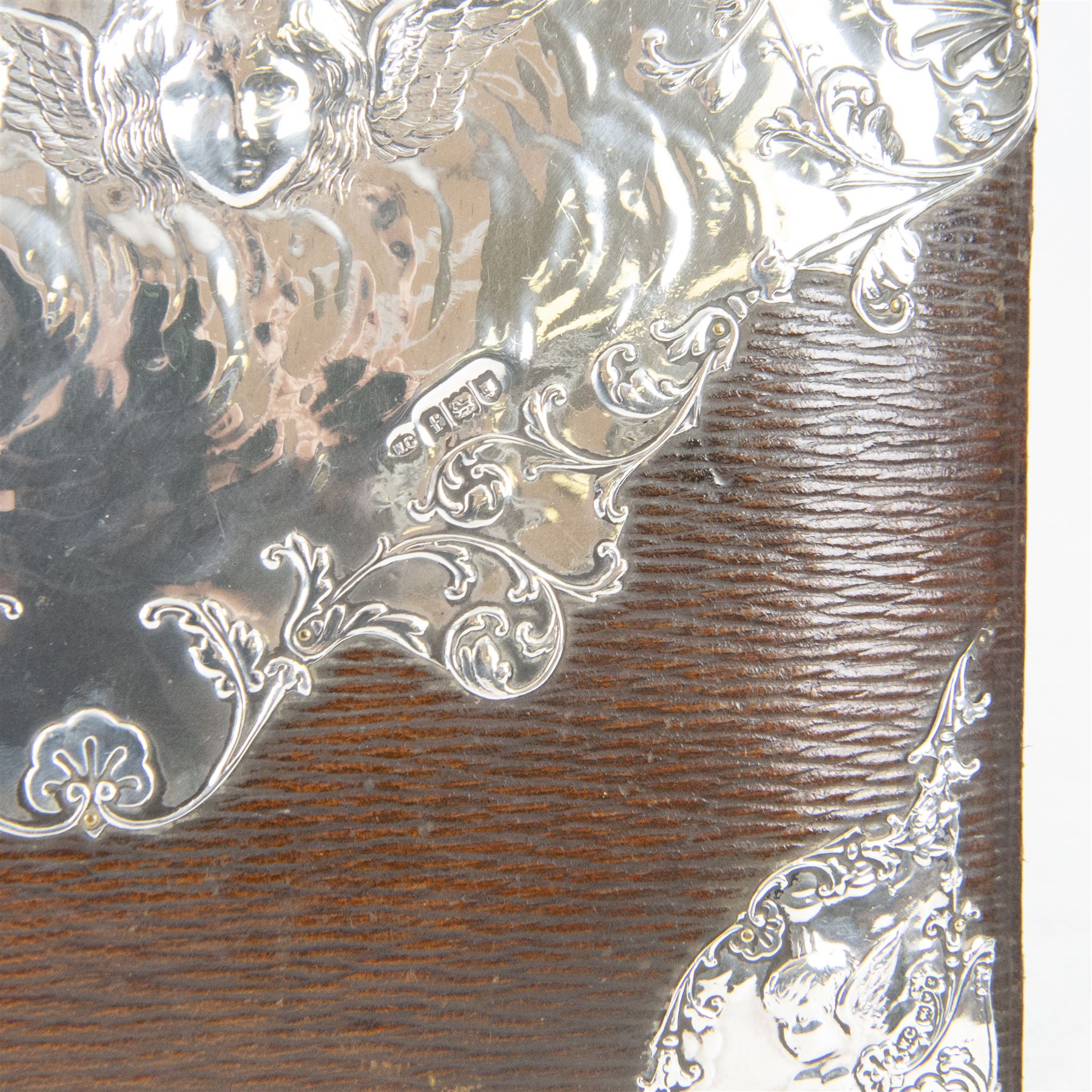 Edwardian silver mounted stationery box and silver mounted blotter, the box of rectangular form with curved front with applied repousse silver panels of putti within a scrolling foliate edge, the hinged cover opening to reveal an emerald green silk lined interior, the blotter with conforming silver mounted panels, each hallmarked William Comyns & Sons, London 1901, box H20cm W31cm D14cm, blotter H32cm W26.5cm