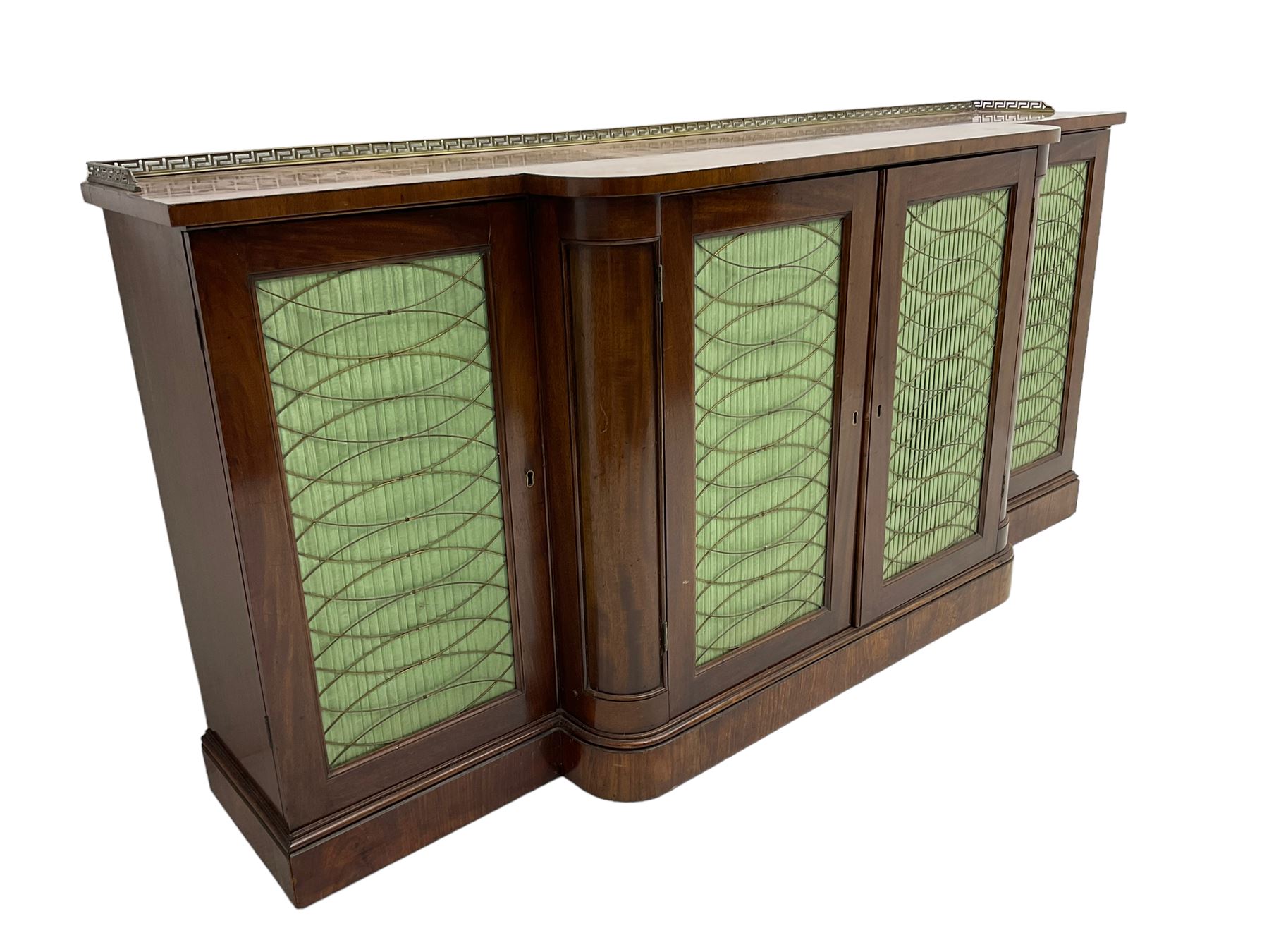 19th century mahogany break-front sideboard, raised brass gallery back with Greek key design, fitted with four cupboard doors, their pleated green fabric overlain with gilt metal grilles, lower moulded edge over plinth base