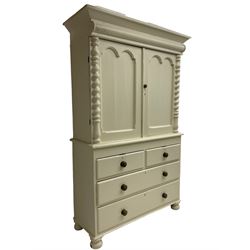 Victorian cream painted pine cupboard-on-chest or housekeeper's cupboard, projecting cornice over two double-arch panelled cupboard doors enclosing two shelves, flanked by spiral turned uprights, base fitted with two short over two long drawers, on bun feet
