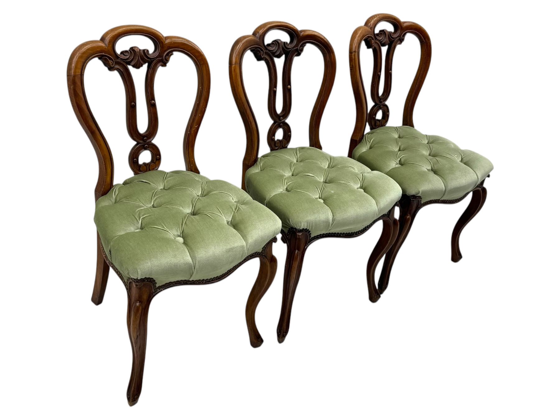 Set of six carved Victorian walnut balloon back dining chairs, button upholstered in green velvet fabric, back with foliate carved decoration supported on scroll form legs 