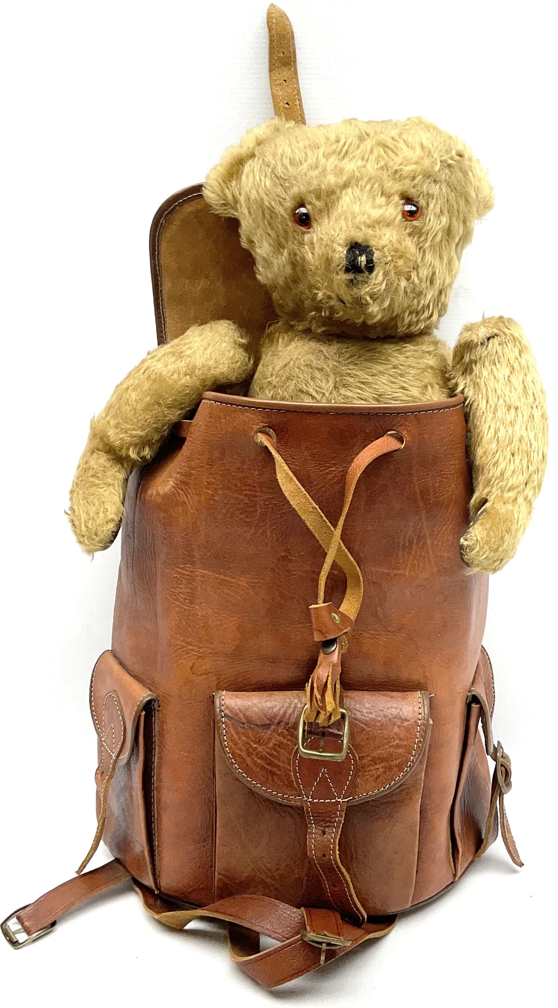 Mid-20th century plush covered teddy bear the revolving head with applied eyes, vertically stitched nose and jointed limbs with rexine pads H58cm; together with a leather backpack (2)