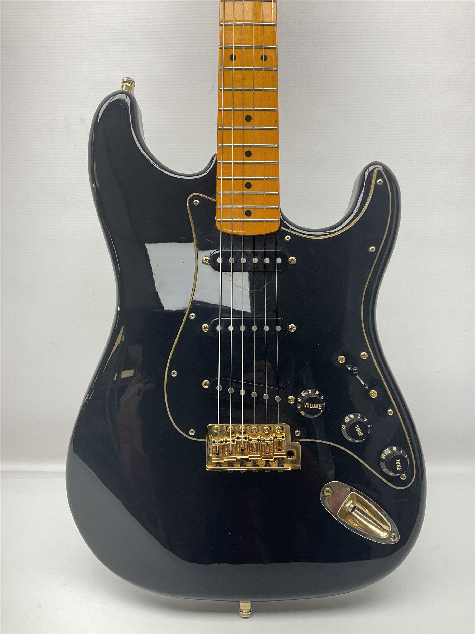 Copy of a Fender Stratocaster electric guitar in black with Wilkinson bridge, lock-in tuners, synchronised tremolo and various patent numbers; L99cm; in hard carrying case with strap and digital tuner