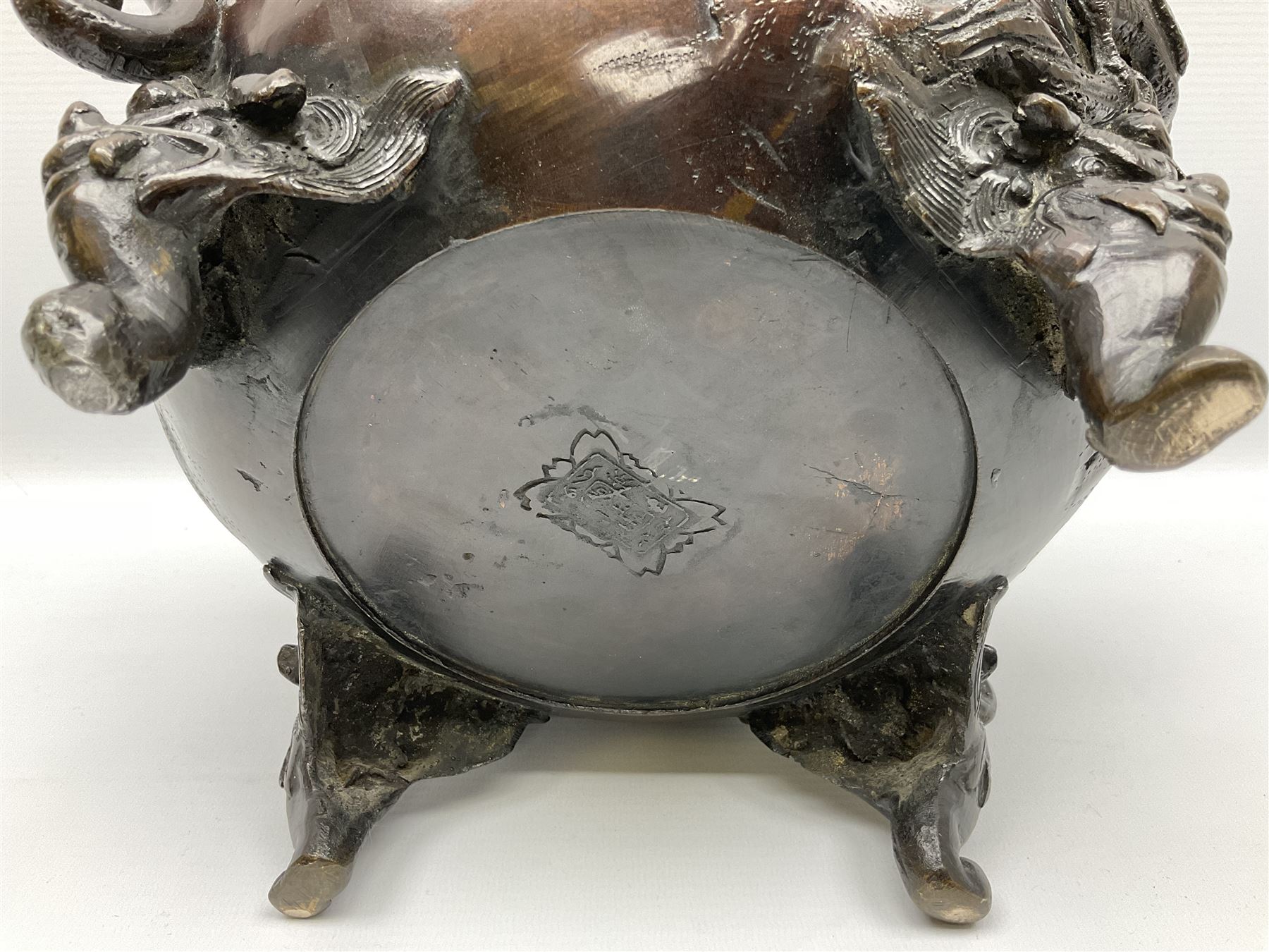 Japanese bronzed koro, the body of globular form with twin cast zoomorphic mask handles, decorated in relief with birds upon blossoming branches, against a ground incised with rushes and peonies, the flat toped domed cover with pierced band and surmounted by a cast figure of a Foo dog, the whole upon three zoomorphic mask feet, with impressed character type mark beneath, H35.5cm