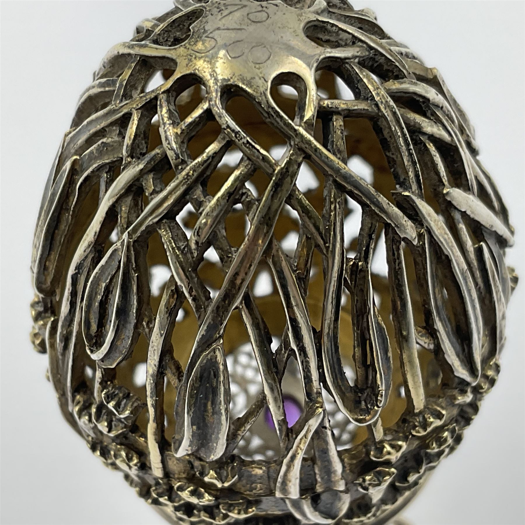 Modern silver limited edition Easter egg, no. 70/500, the gilt openwork body decorated with cascading bluebells and hinged cover with pierced circular panel set with a single faceted purple stone, opening to reveal a gilt interior, upon silver stand with three scrolling pad feet, each hallmarked St James House Company, London 1981, height including stand 8cm