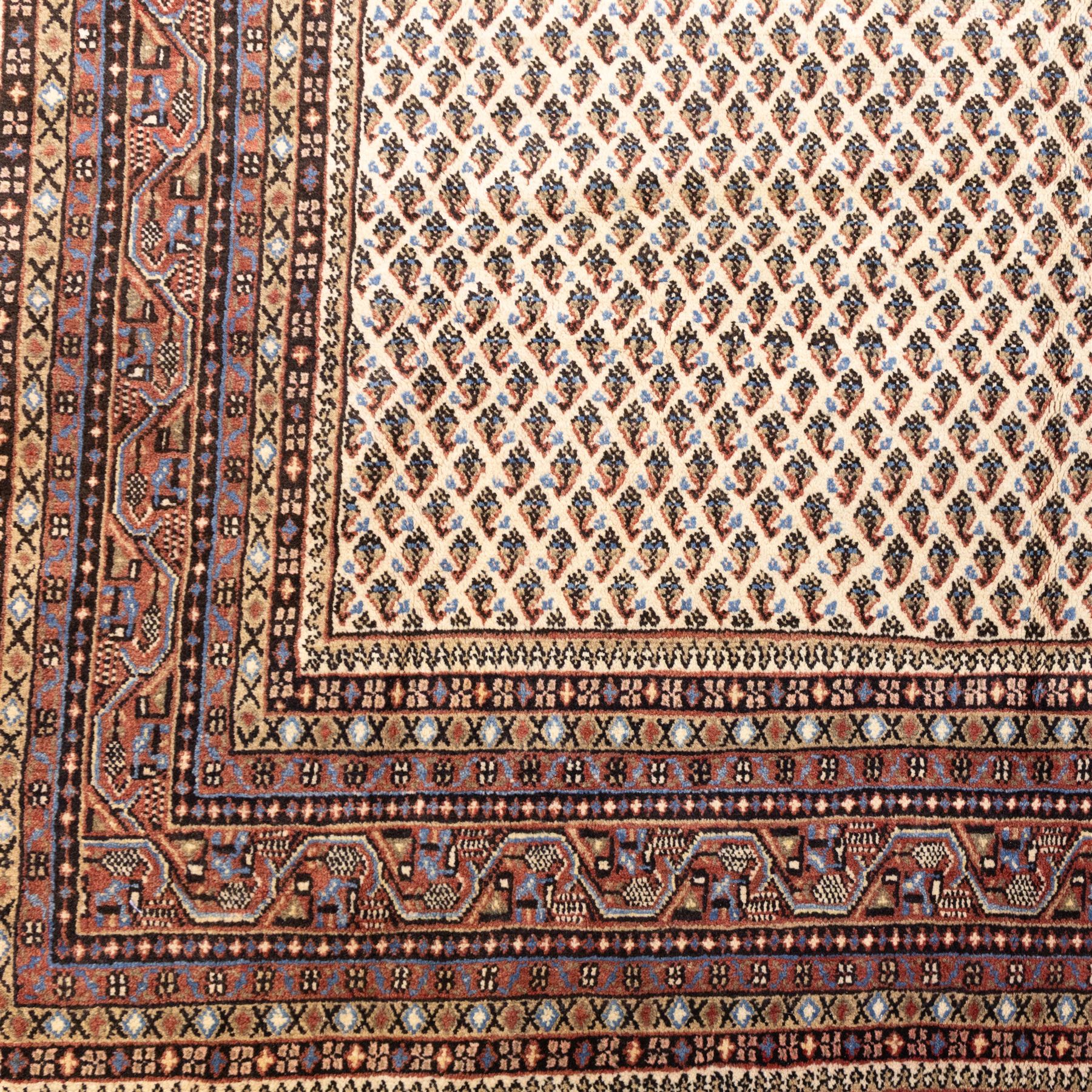 West Persian Botteh-Mir hand-knotted rug, ivory field decorated with an overall dense lattice design of small repeating boteh motifs in muted blue, rust, and brown tones, enclosed by a series of narrow borders incorporating stylized geometric and floral patterns with cotton fringe ends 