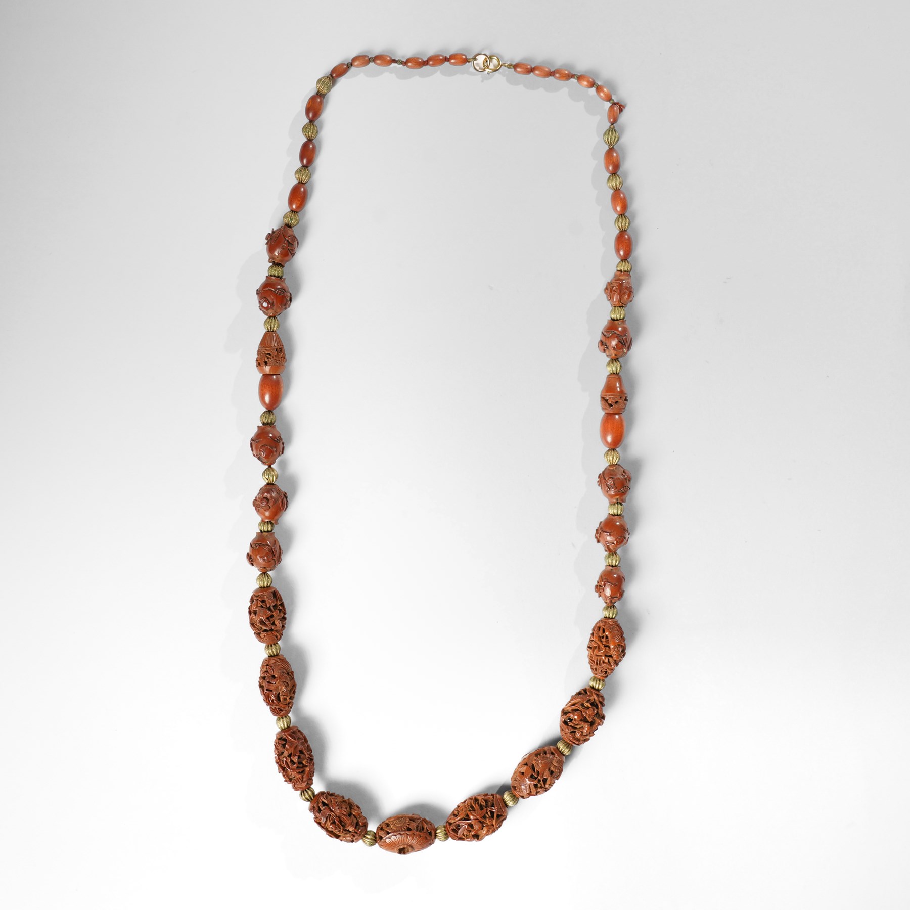 Chinese Hediao necklace, comprising twenty-one pierced and carved seeds strung with smaller beads, the carvings depicting birds among foliage, crabs and fish, figures and warriors, and other traditional scenes, length 82cm 