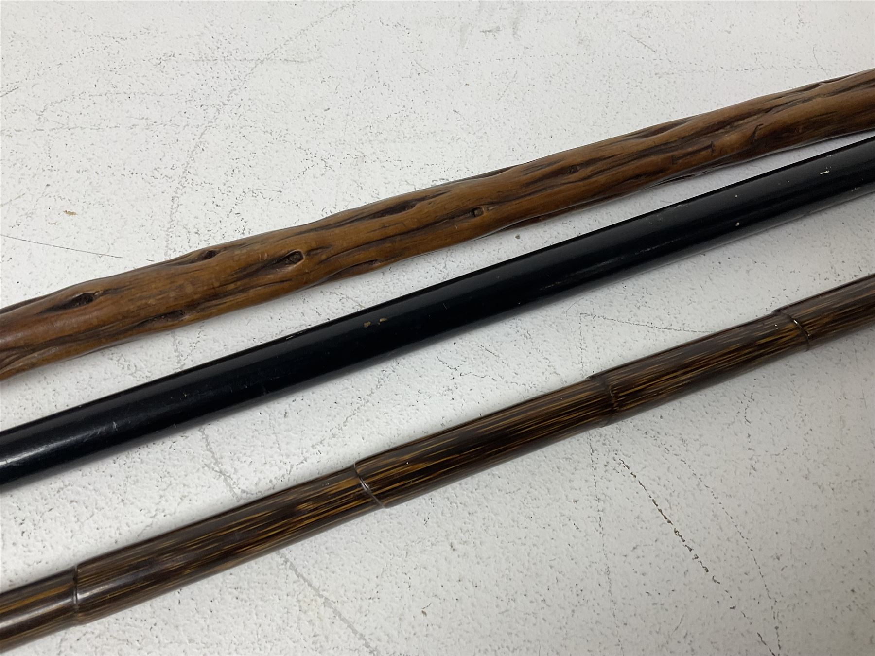 19th century painted bamboo walking cane, the handle carved as a fox with glass eyes, with gilt metal stamped LB, together with an ebonised wooden walking stick, with horn pommel and hallmarked silver collar and a curved wooden walking stick, with monogrammed white metal cap, tallest L90cm